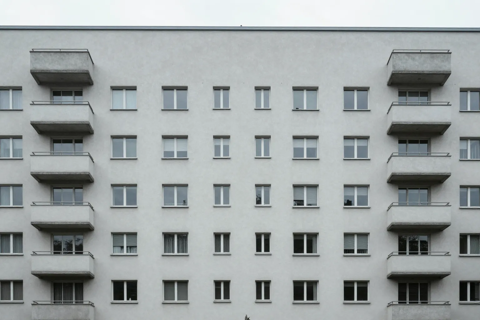 Frontalaufnahme der schlichten Fassade eines Mehrfamilienhauses mit Balkonen